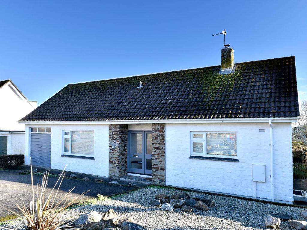 une maison blanche avec un toit noir dans l'établissement Treverrion, à Gorran Haven