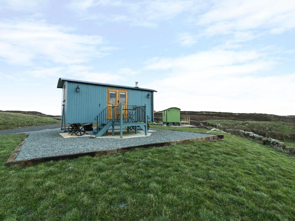 a small blue house on a grassy hill at Llety'r Bugail in Holyhead