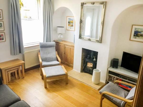 a living room with a chair and a fireplace at Croft Cottage in Pateley Bridge