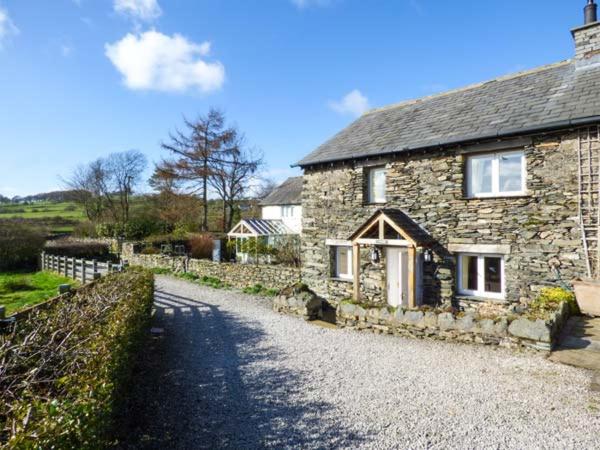 een stenen huis met een grindweg ervoor bij Kestrel Cottage in Grange Over Sands