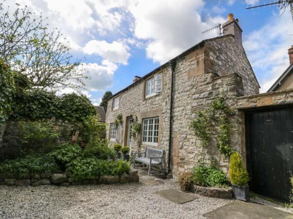 a stone house with a bench in front of it at Rose Cottage in Bakewell