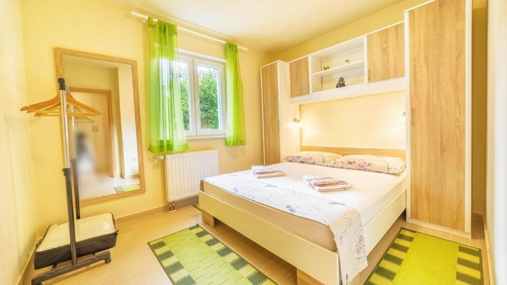 a bedroom with a bed with green curtains and a mirror at Apartment Luna in Srima