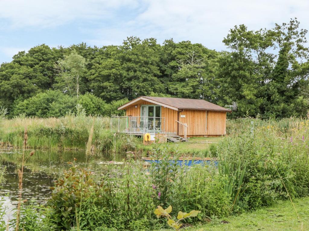 a cabin in a field next to a pond at Lakeside Lodge in East Harling