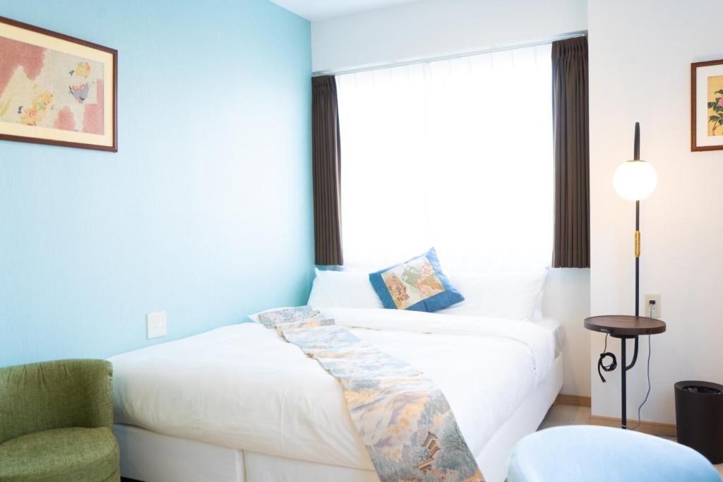 1 dormitorio con 1 cama blanca y 1 silla en Kiba no Tsuru Carane Hotel - Vacation STAY 09997v en Tokio