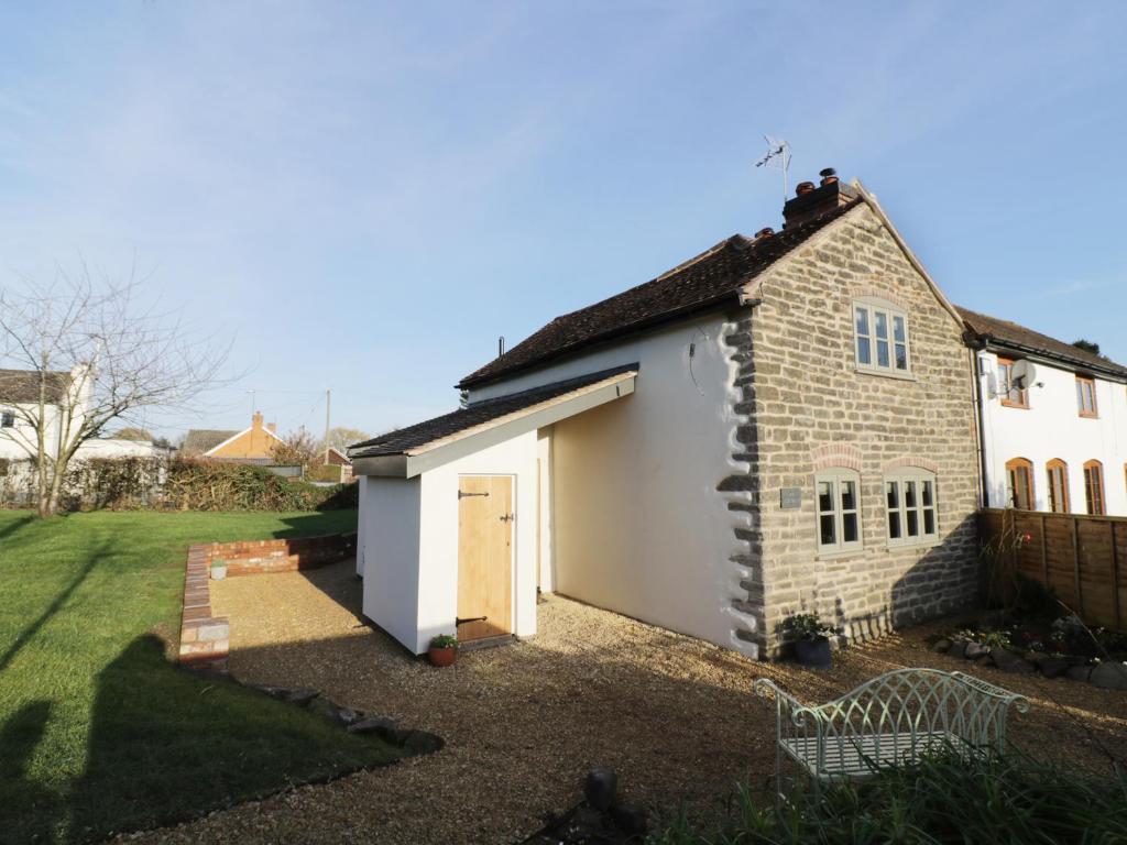 uma pequena casa de tijolos com uma garagem branca em Ivy Cottage em Great Malvern