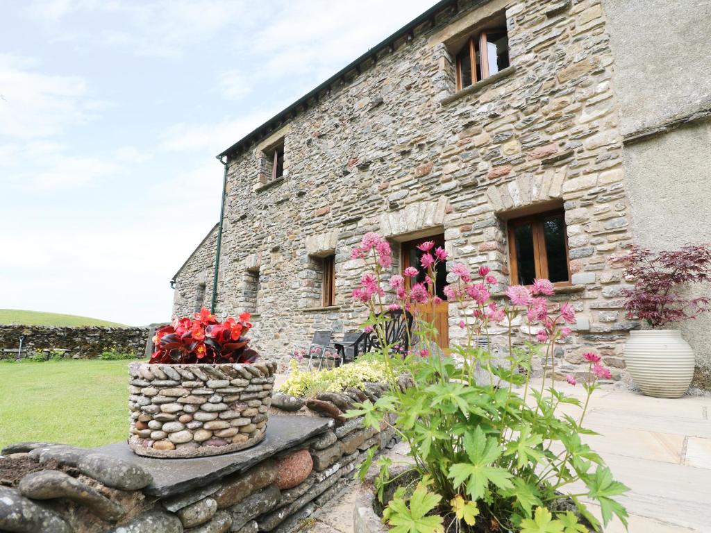 a stone building with flowers in front of it at Grayrigg Foot Stable in Grayrigg