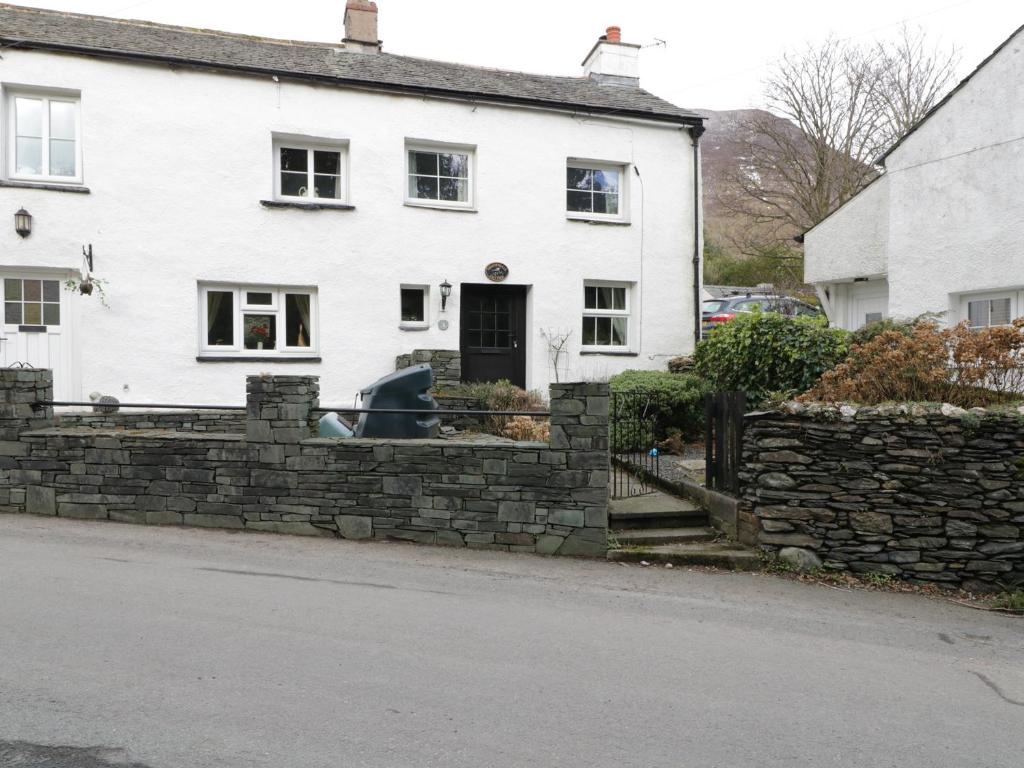 a white house with a stone fence in front of it at Nightingale Cottage in Threlkeld