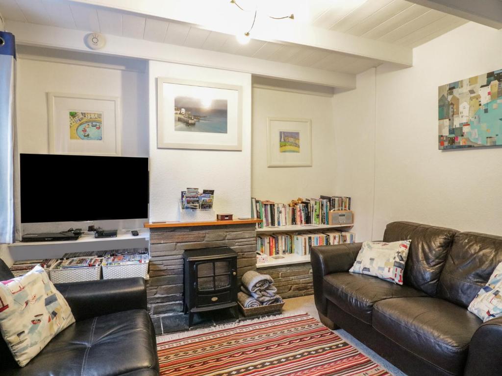 a living room with two leather couches and a flat screen tv at Daisy Cottage in Perranporth