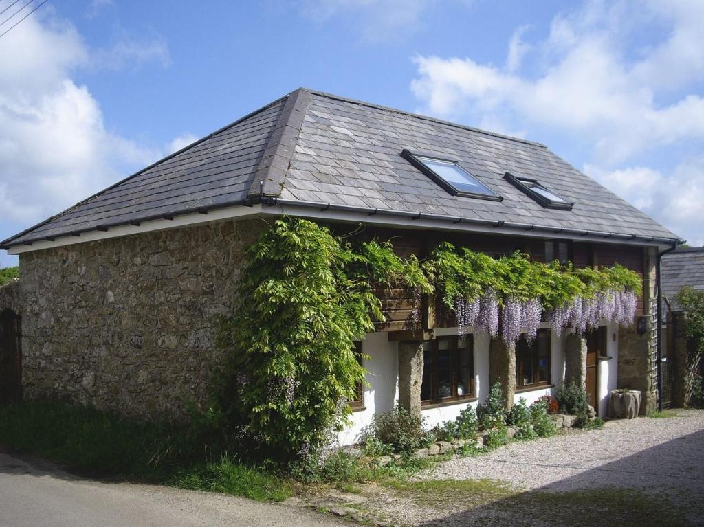 Throwleigh的住宿－The Linhay，旁边是一座有紫藤的房子