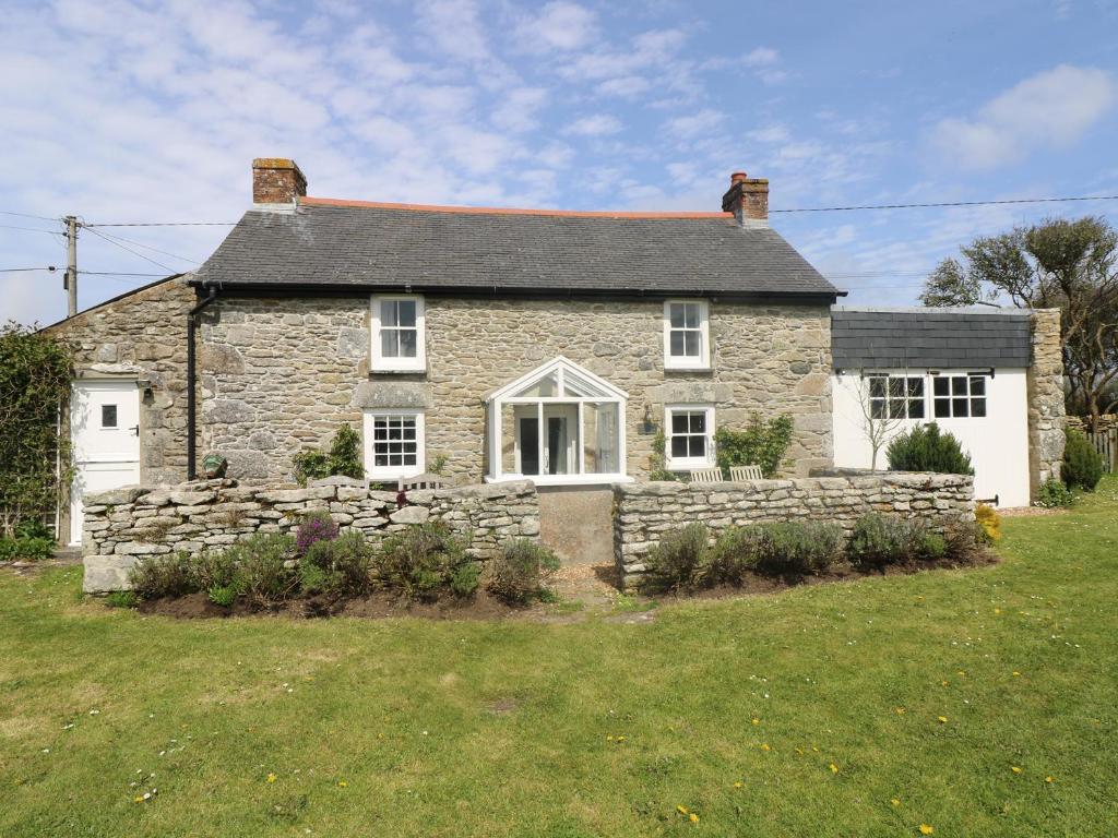 an old stone house with a stone wall at Evergreen in Breage