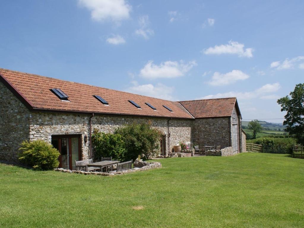 un antiguo edificio de piedra con un patio de césped en Battens en Northleigh