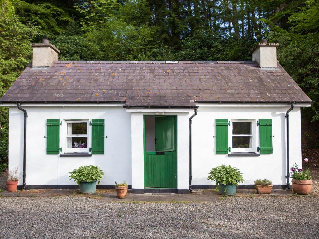 een wit huis met groene luiken en potplanten bij Mr McGregors' Cottage in Gortin