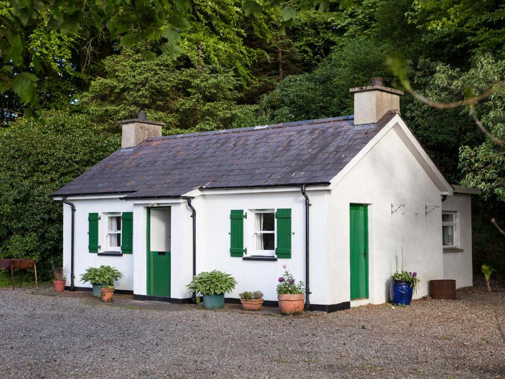 a small white house with green shutters and plants at Mr McGregors' Cottage in Gortin