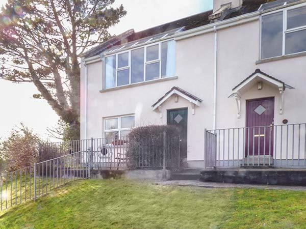 a white house with a red door and a fence at Number 12 in Mulranny