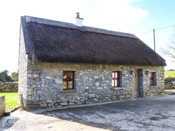 a stone building with two windows and a roof at The Well House in Kinvara