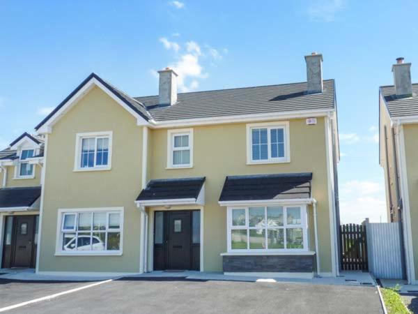 a large yellow house with a driveway at 63 Moinin in Kilkee