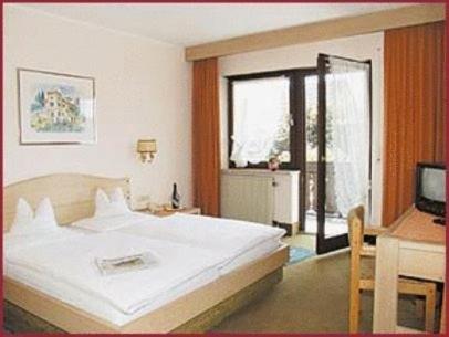 a bedroom with a large white bed and a desk at Hotel Hiemer in Memmingen