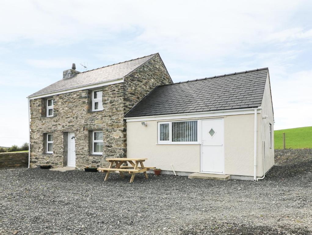 a stone cottage with a picnic table in front of it at Felin Manaw in Bryngwran