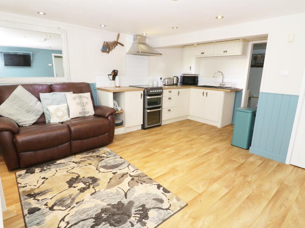 a living room with a couch and a kitchen at The Hideaway in Benllech