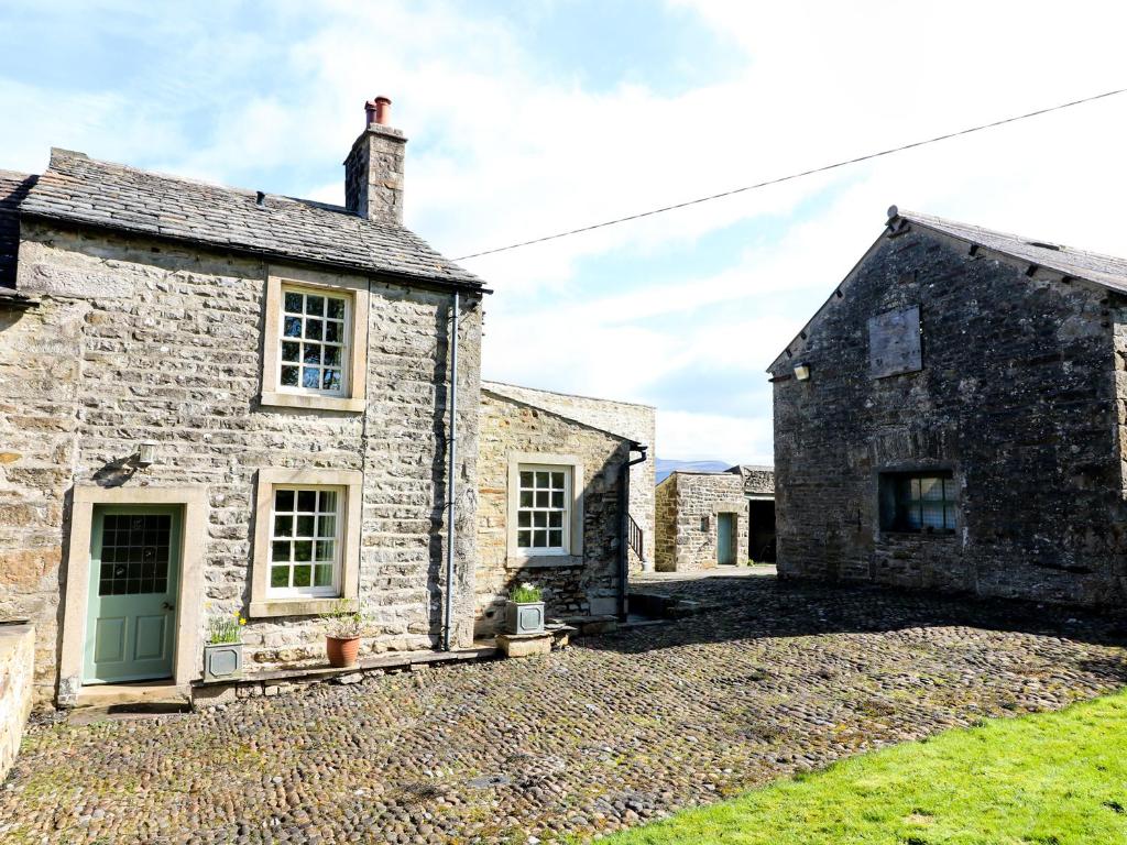 an old stone house with a green door at Mill Dam Farm Cottage in High Bentham