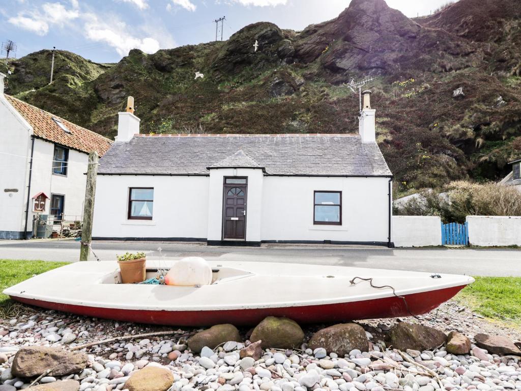 a boat sitting on the rocks in front of a house at St Magnus Haven in Pennan