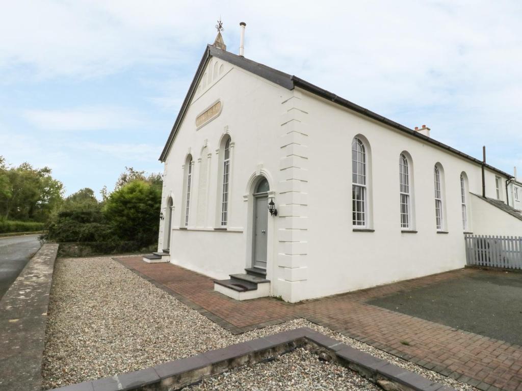 an old white church with a road in front of it at Capel Bryn Bachau in Pwllheli