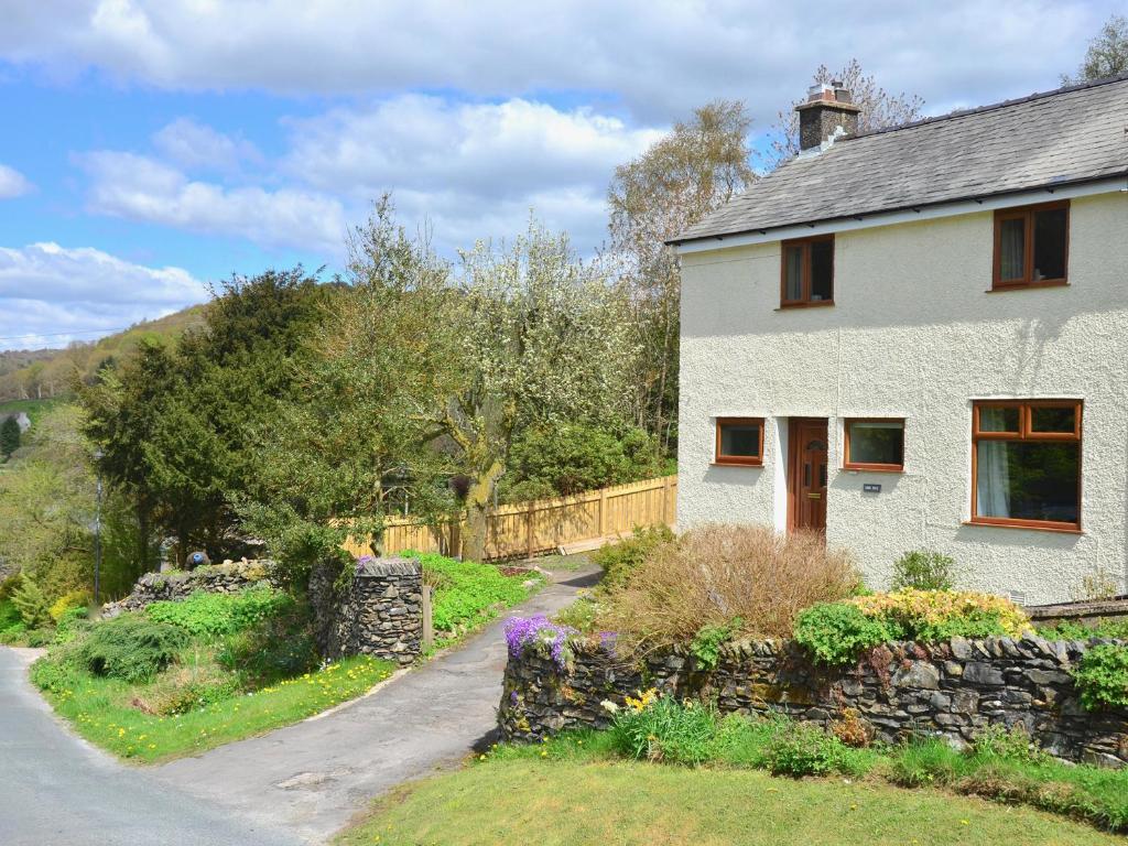 una casa bianca con un muro di pietra accanto a una strada di Ling Fell Cottage a Ulverston