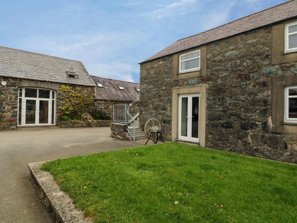 uma vista exterior de uma casa de pedra com um quintal em Dinas em Pwllheli