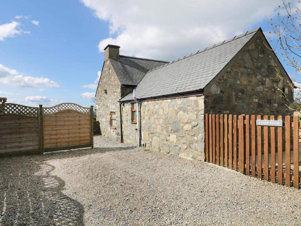 an old stone building with a wooden fence at Cegin Foch in Chwilog