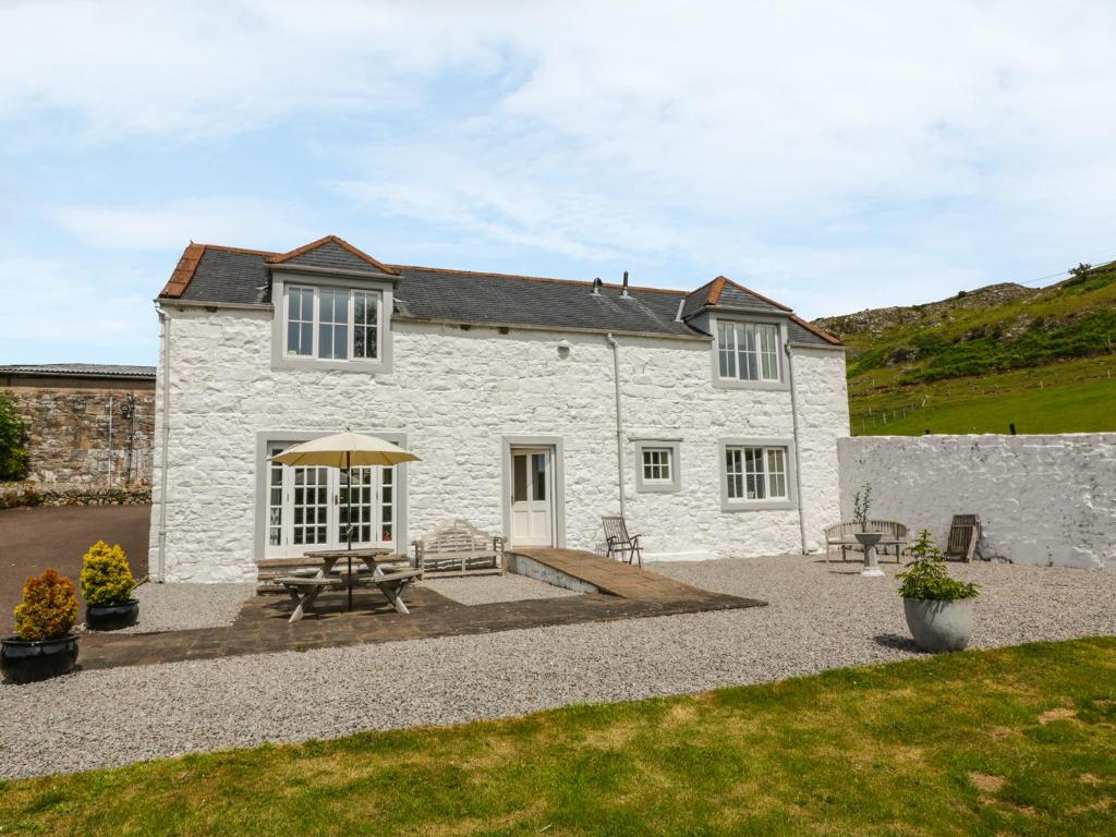 a white stone house with two picnic tables in front of it at Bracken Holiday Cottage in Dalbeattie