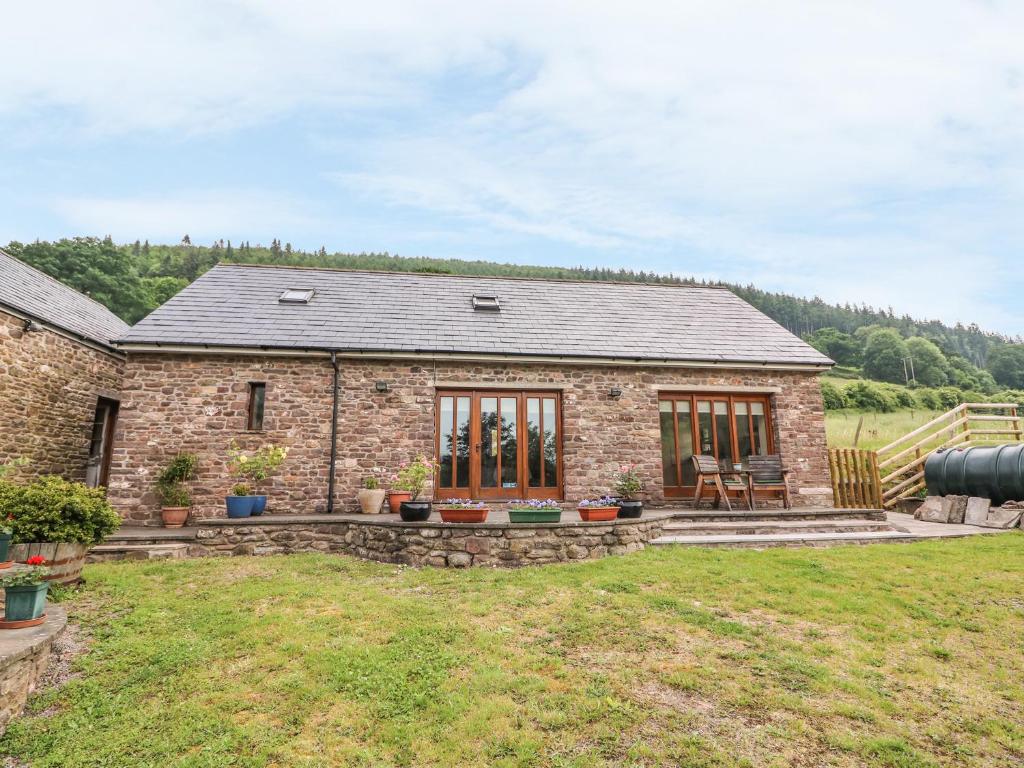 a stone house with a patio in a yard at The Barn in Crickhowell