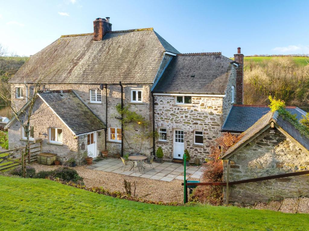 una antigua casa de piedra con un patio frente a ella en 2 Bittadon Cottages en Barnstaple