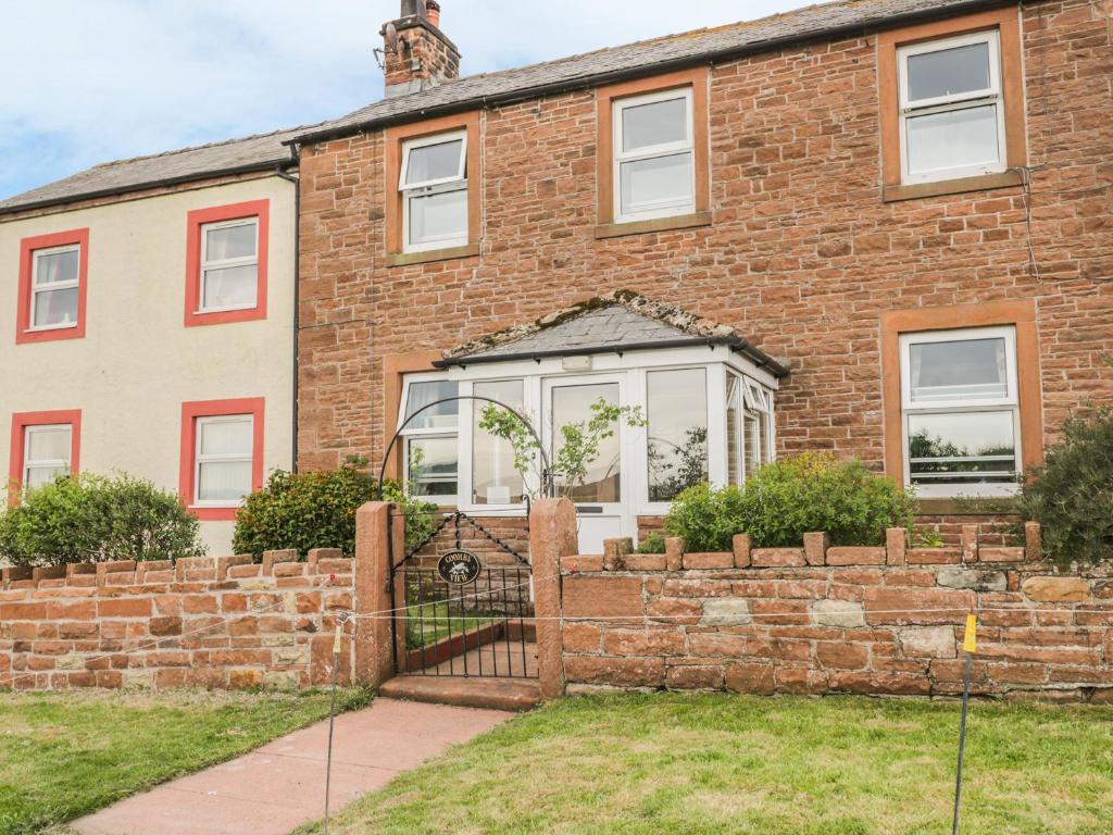 a brick house with a fence in front of it at Coombs View in Low Hesket