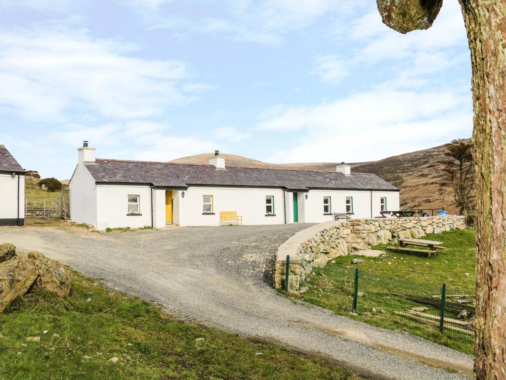 uma casa branca com uma estrada de cascalho em frente em Pat White's Cottage em Rostrevor