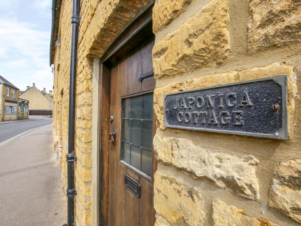 a sign on the side of a building at Japonica Cottage in Bourton on the Water