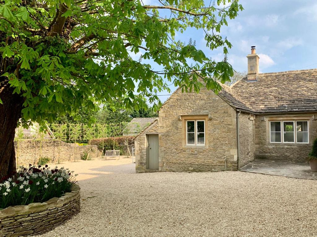 a stone house with a tree and a driveway at The Old Dairy in Burford