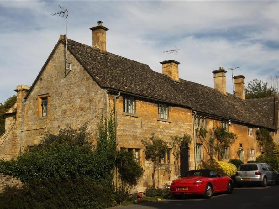 an old stone building with a red car parked in front at Shepherds Hay in Broadway