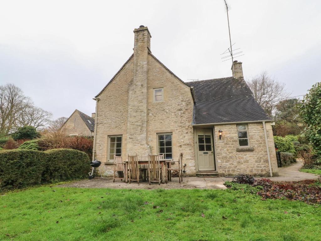 an old stone house with a table in the yard at Spring Cottage in Cirencester