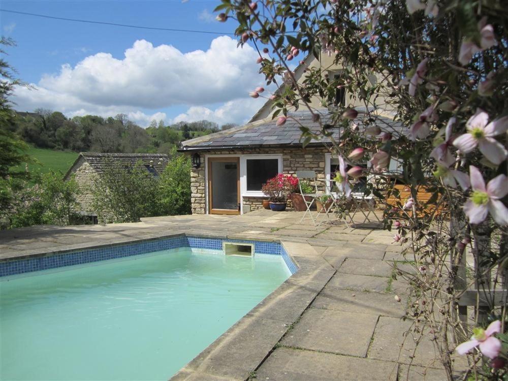 a swimming pool in front of a house at Shrove in Chedworth