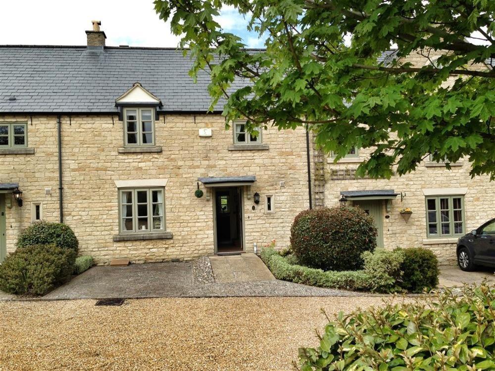 a brick house with a door and a car parked in front at Stow Cottage in Stow on the Wold