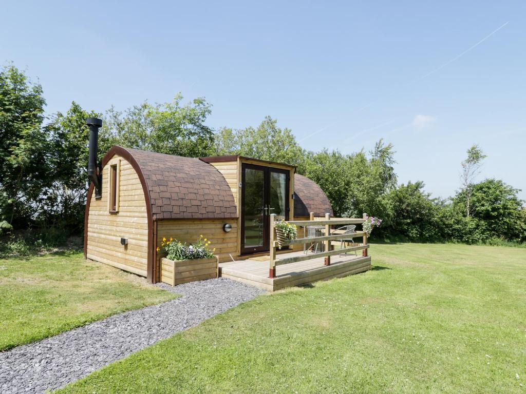 a large wooden cabin with a deck in the grass at Idris Pod in Tremeirchion