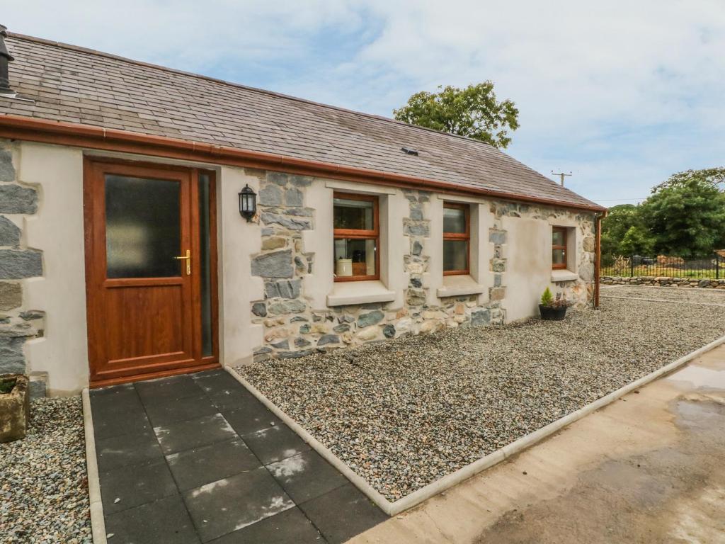 a stone cottage with a wooden door at Y Deri Cottage in Llandwrog