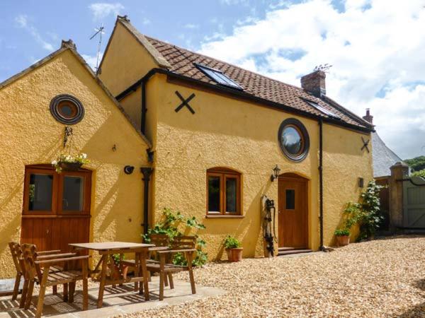 una casa con una mesa y sillas frente a ella en The Old Cottage en Weston-super-Mare