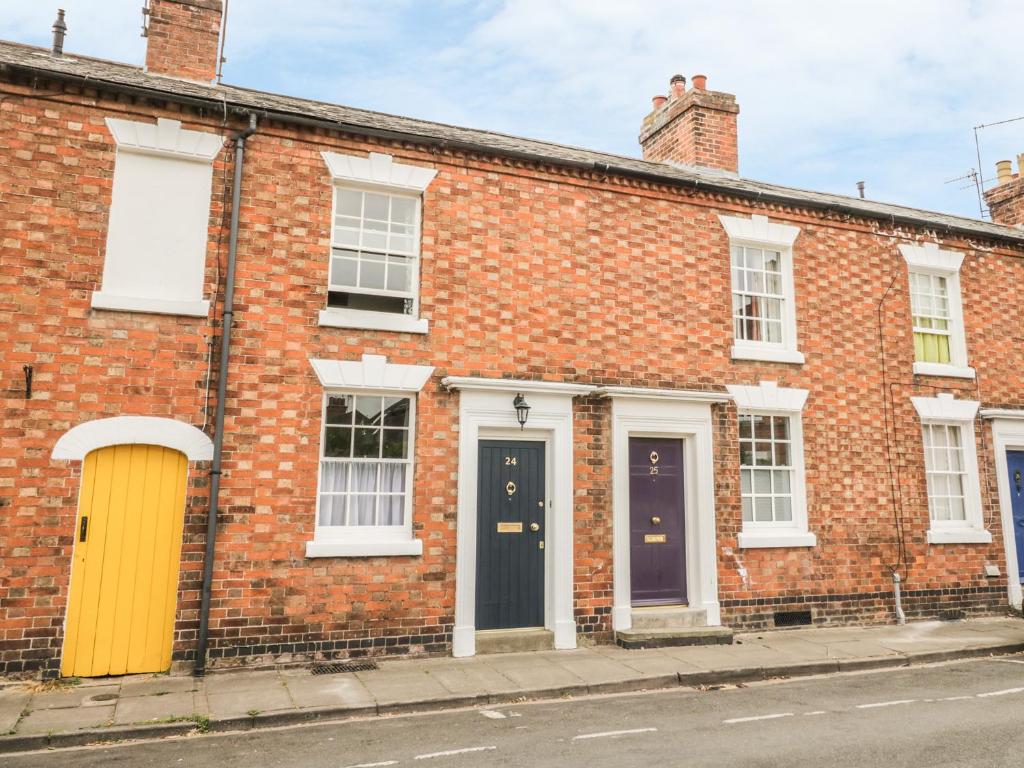 um edifício de tijolos com duas portas e uma porta amarela em 24 College Lane em Stratford-upon-Avon