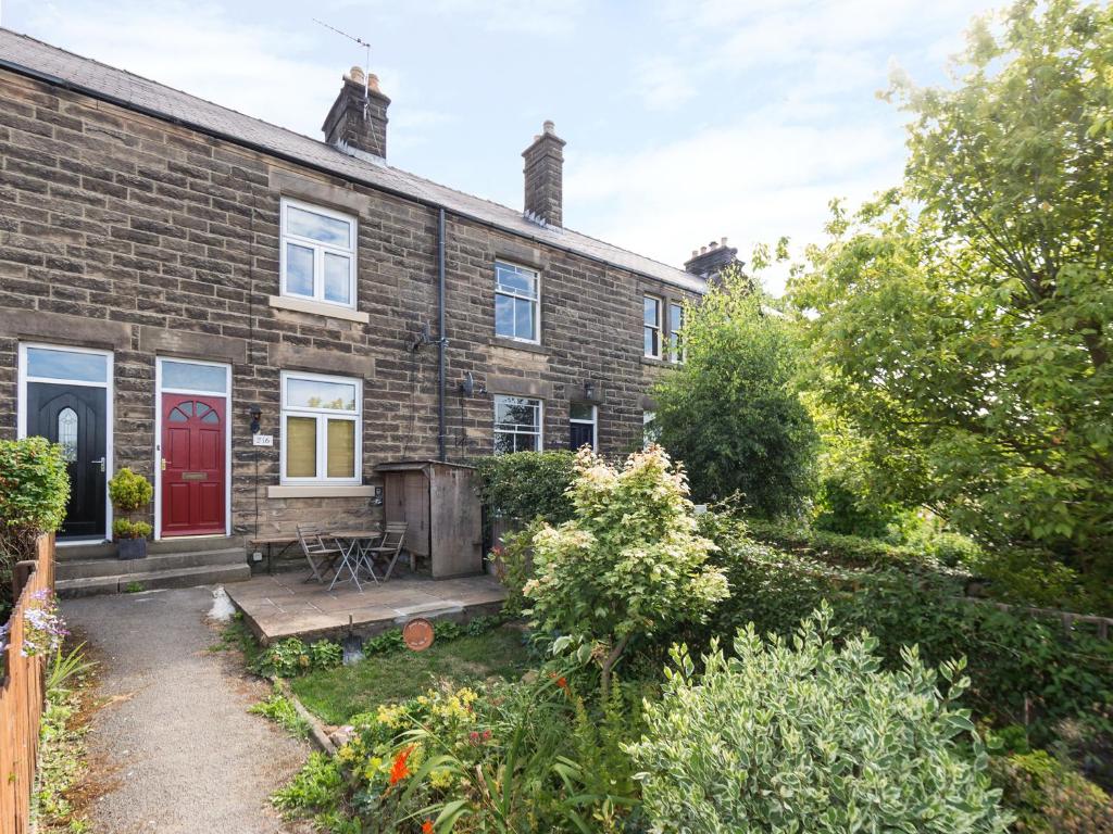 a brick house with a red door and a yard at Bobbin Cottage in Matlock