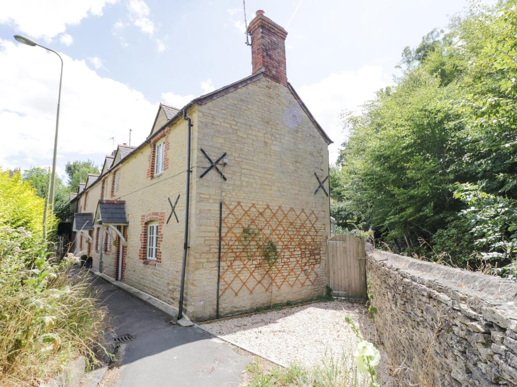 Una casa vieja con una valla a un lado. en Blenheim Edge, The Causeway, en Woodstock