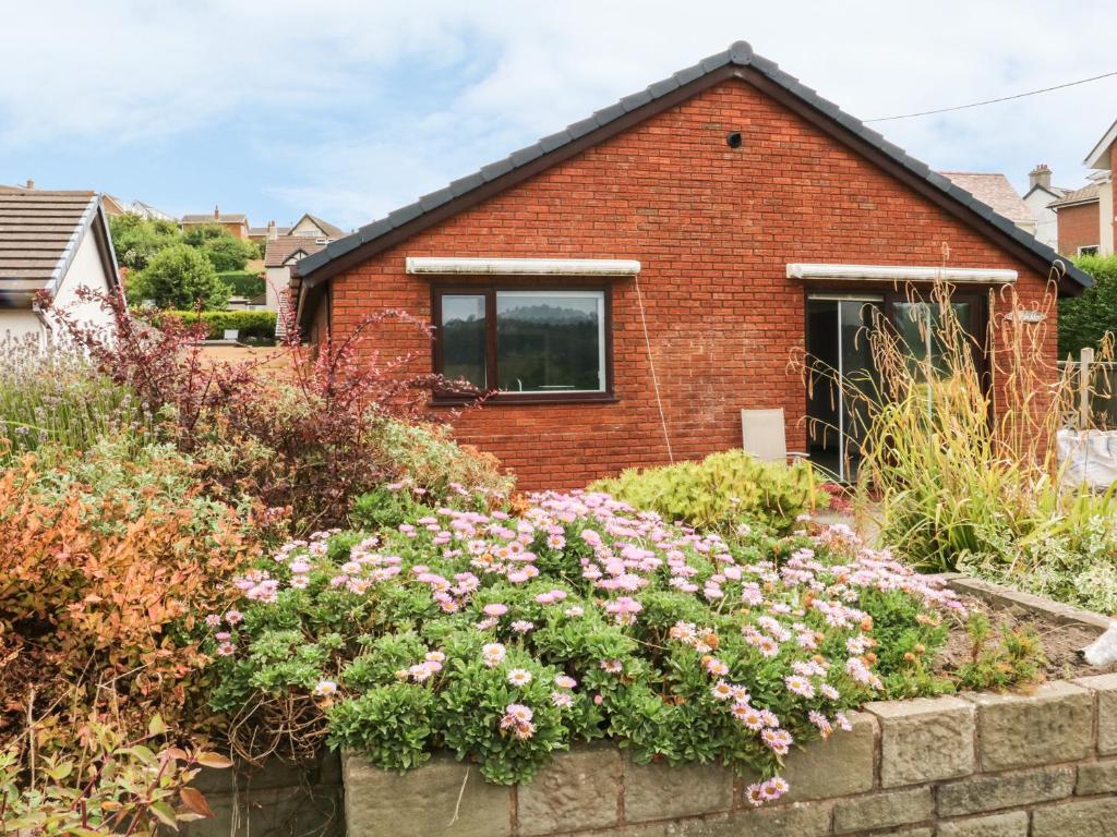 a brick house with flowers in front of it at 3 Trem Afon in Colwyn Bay