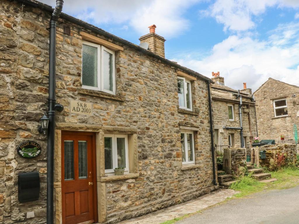 an old stone house with a red door on a street at High Head in Richmond