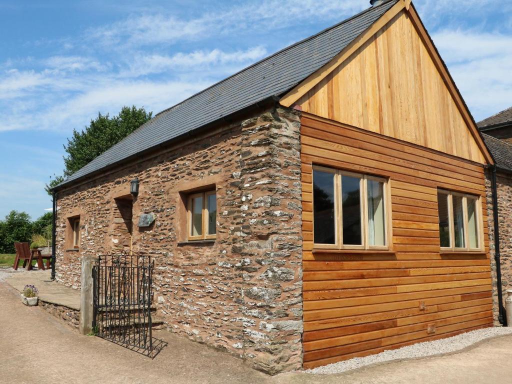 un edificio de piedra y madera con techo negro en The Cottage en Watchet