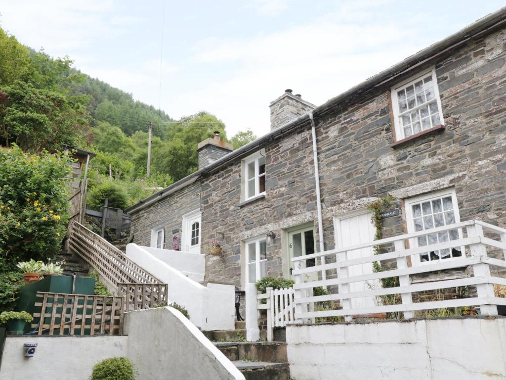an old stone house with a staircase leading up to it at Tanrallt in Machynlleth